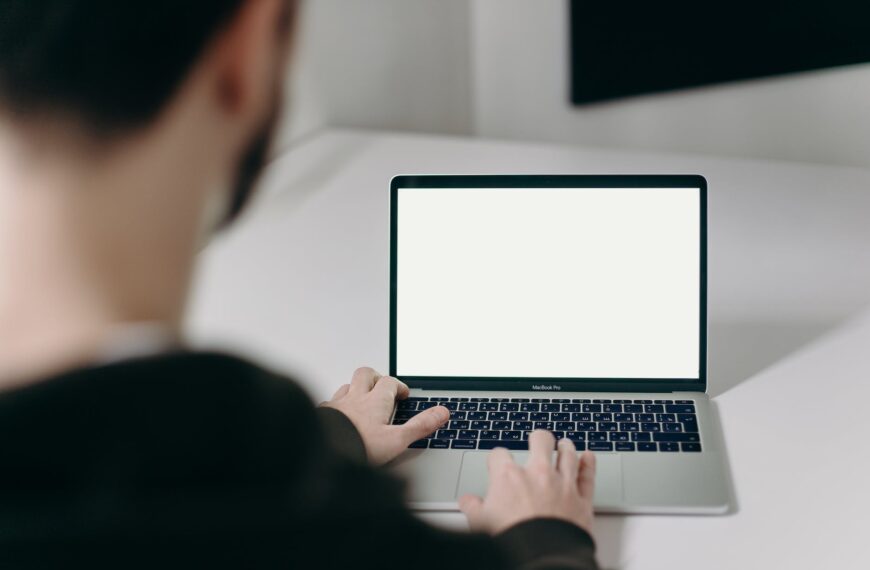 person using macbook pro on white table