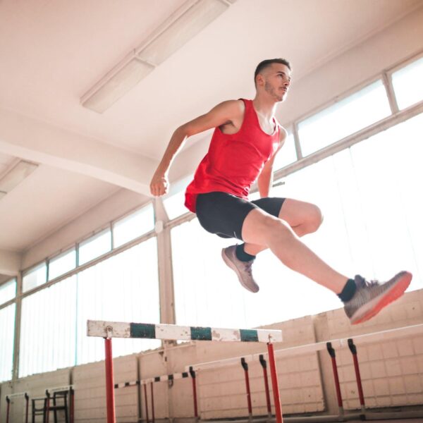 woman in red tank top jumping on obstacle