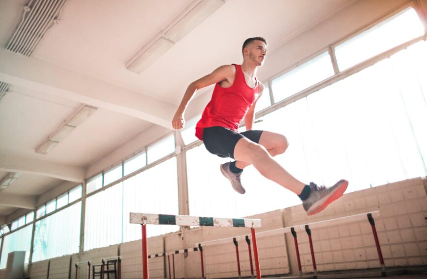 woman in red tank top jumping on obstacle